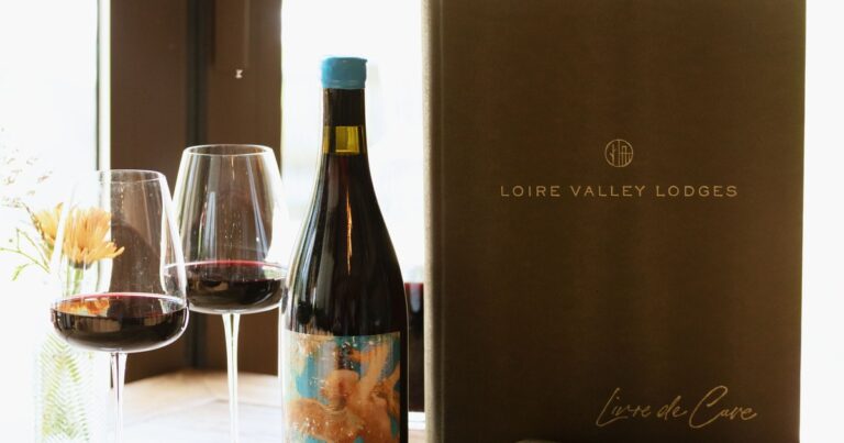 Le Livre de Cave de Loire Valley Lodges avec une bouteille et deux verres de vin rouge
